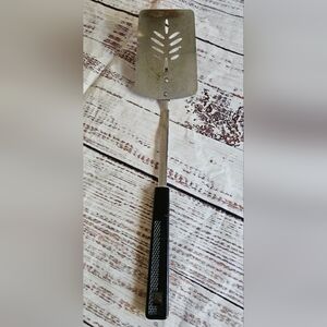 Vintage slotted metal spatula with black textured handle. Marked “Japan” on the